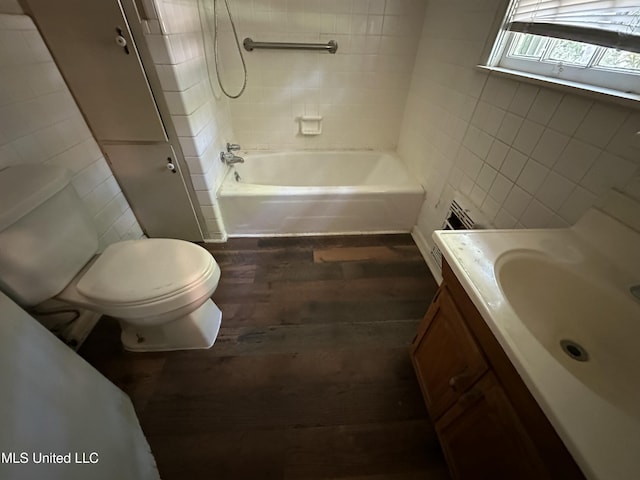 full bath with toilet, vanity, wood finished floors, and tile walls