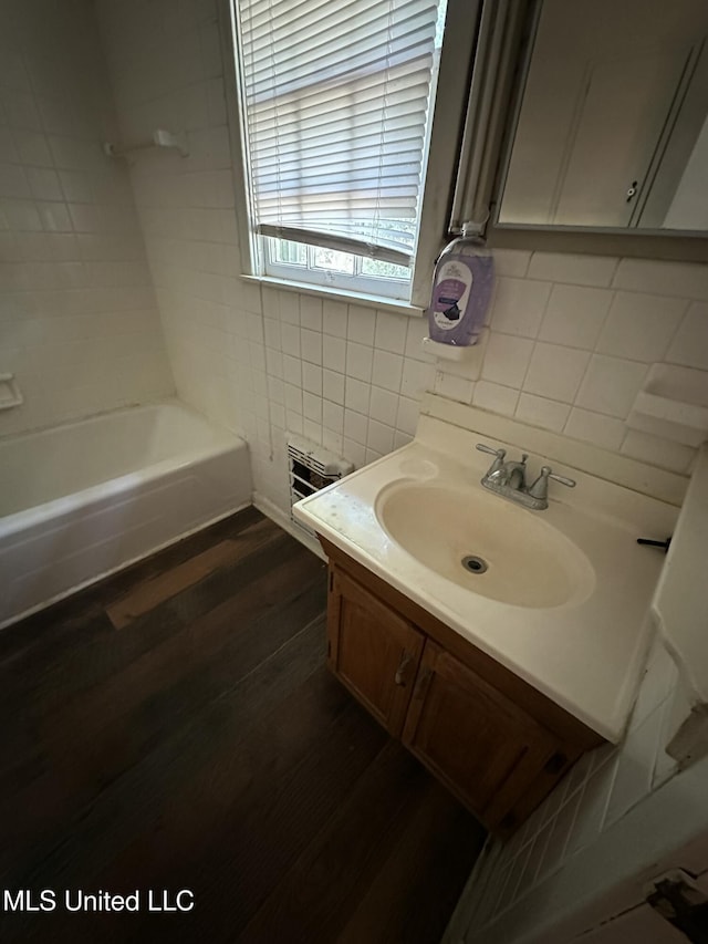 full bathroom with backsplash, wood finished floors, vanity, tile walls, and shower / tub combination