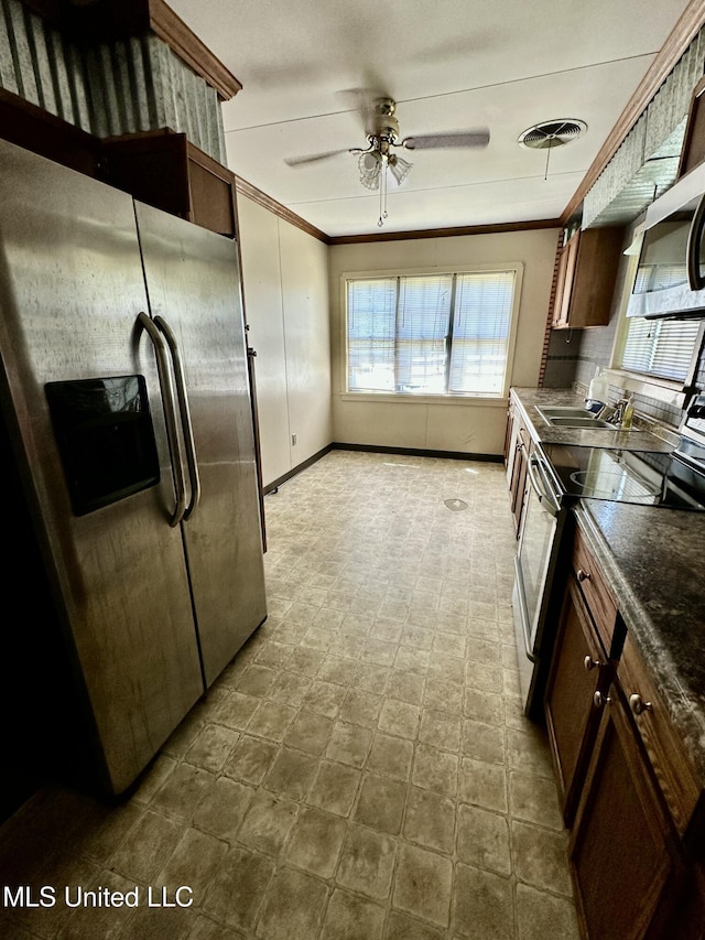 kitchen with stainless steel appliances, dark countertops, baseboards, visible vents, and crown molding