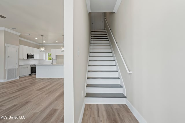 stairway featuring a notable chandelier, ornamental molding, and hardwood / wood-style flooring