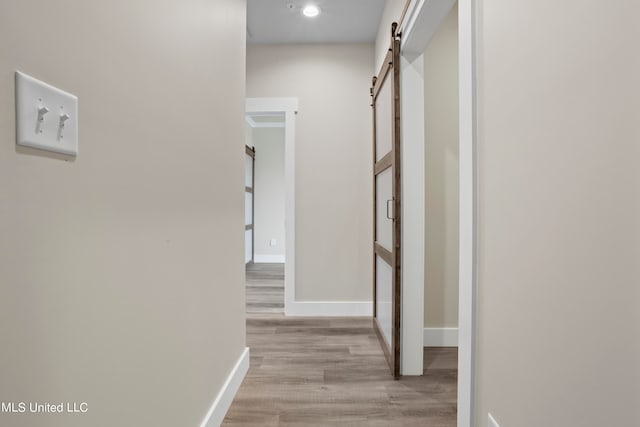 hallway with a barn door and light hardwood / wood-style flooring