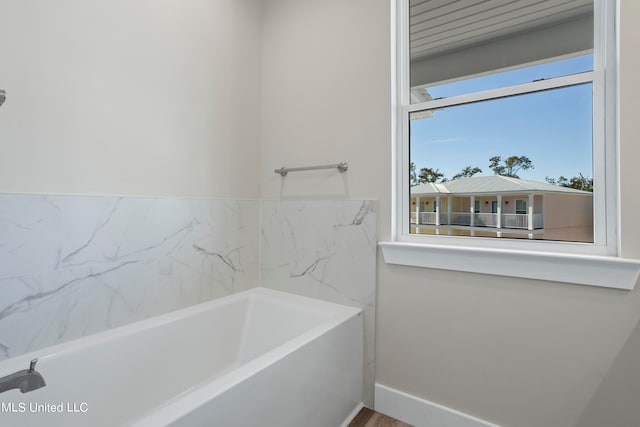 bathroom with hardwood / wood-style floors and a bath