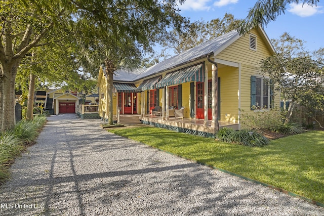 view of front of house featuring a porch, a garage, an outbuilding, and a front lawn