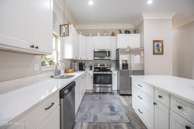 kitchen featuring appliances with stainless steel finishes, white cabinetry, ornamental molding, and sink