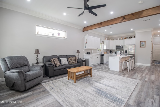 living room with ceiling fan, beam ceiling, light hardwood / wood-style floors, and crown molding