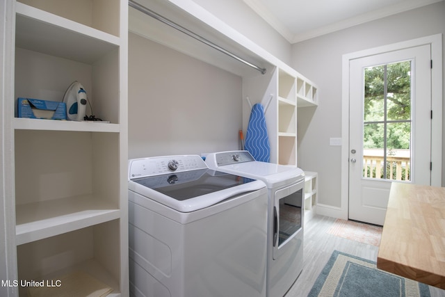 laundry room with light wood-type flooring, separate washer and dryer, and crown molding