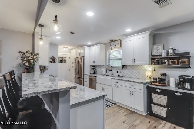 8707 Pine Ridge Ct, Diamondhead, MS 39525 - kitchen with stainless steel appliances, white cabinets, a peninsula, a kitchen bar, and decorative backsplash