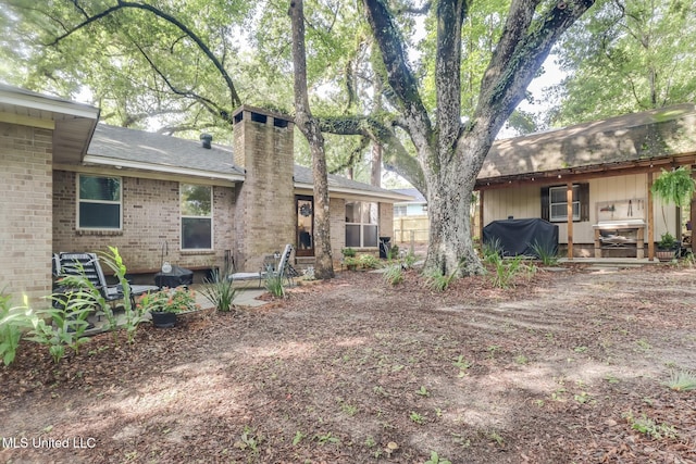 8707 Pine Ridge Ct, Diamondhead, MS 39525 - back of house featuring brick siding, a chimney, a patio area, and roof with shingles