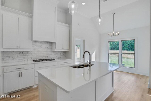 kitchen with white cabinetry, a center island with sink, gas cooktop, decorative light fixtures, and sink