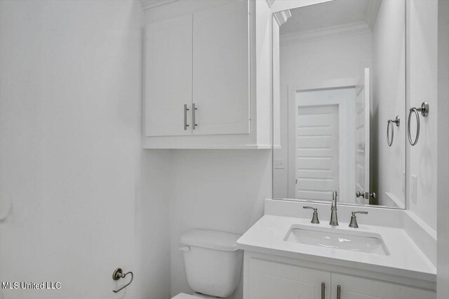 bathroom with toilet, vanity, and ornamental molding