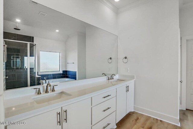 bathroom featuring independent shower and bath, ornamental molding, hardwood / wood-style flooring, and vanity