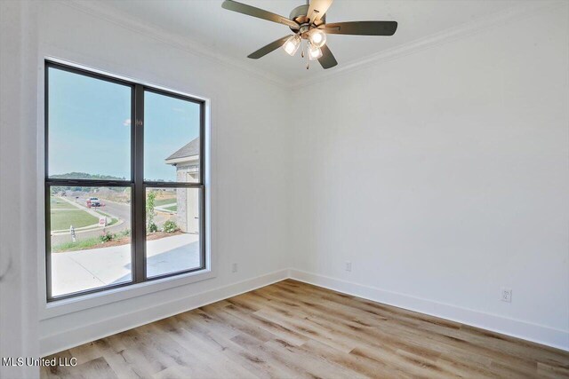 spare room featuring ceiling fan, light wood-type flooring, a wealth of natural light, and crown molding