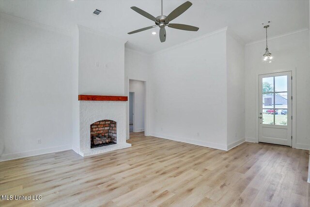 unfurnished living room featuring ceiling fan with notable chandelier, ornamental molding, light hardwood / wood-style floors, and a fireplace