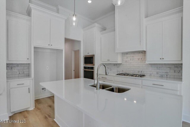 kitchen featuring pendant lighting, white cabinets, sink, stainless steel gas cooktop, and oven