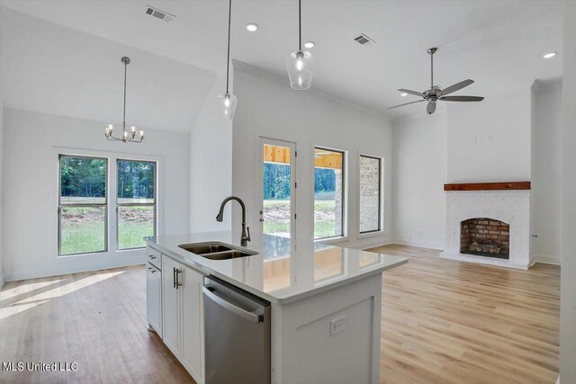 kitchen with white cabinetry, an island with sink, hanging light fixtures, stainless steel dishwasher, and sink