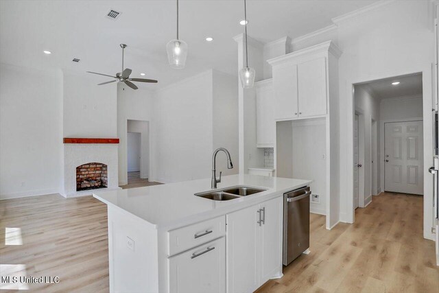 kitchen with pendant lighting, dishwasher, white cabinetry, sink, and a kitchen island with sink