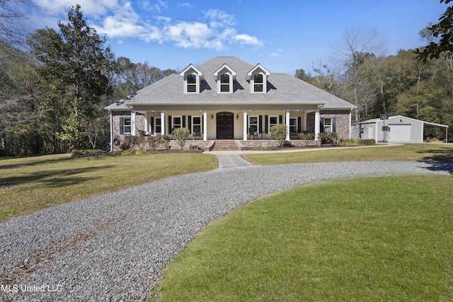 view of front facade featuring a garage, an outbuilding, gravel driveway, covered porch, and a front yard