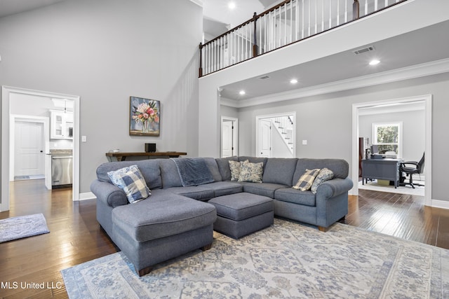 living area with baseboards, crown molding, visible vents, and hardwood / wood-style floors