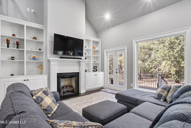 living room with high vaulted ceiling, french doors, a fireplace, and wood finished floors