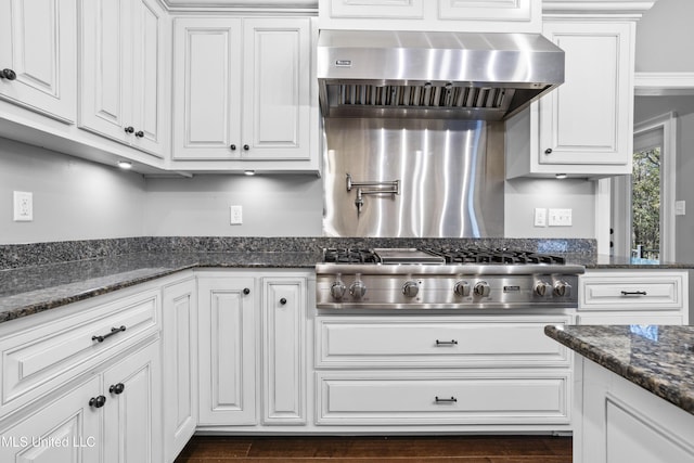 kitchen with wall chimney range hood, stainless steel gas stovetop, dark wood-style floors, and white cabinets