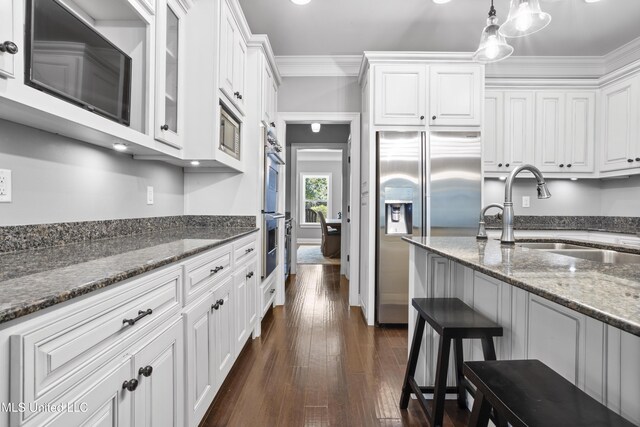 kitchen with dark wood-style flooring, appliances with stainless steel finishes, ornamental molding, white cabinetry, and a sink