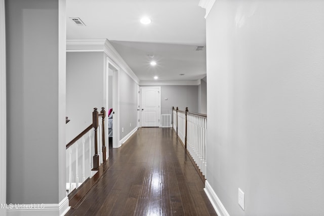 corridor featuring dark wood-style flooring, visible vents, an upstairs landing, baseboards, and ornamental molding