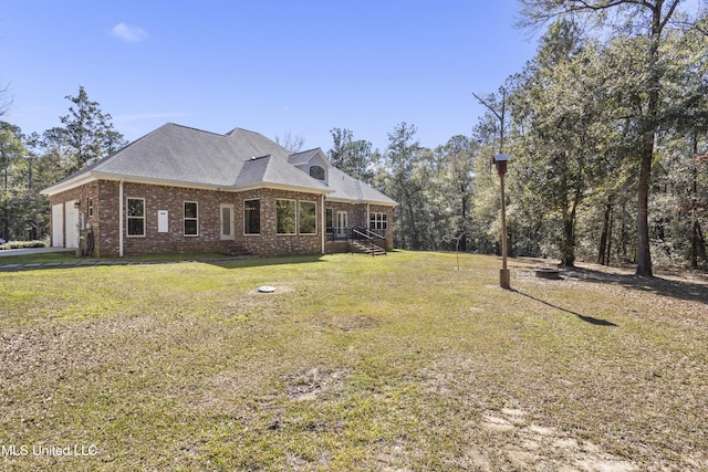 view of home's exterior featuring an attached garage, a yard, a shingled roof, and brick siding