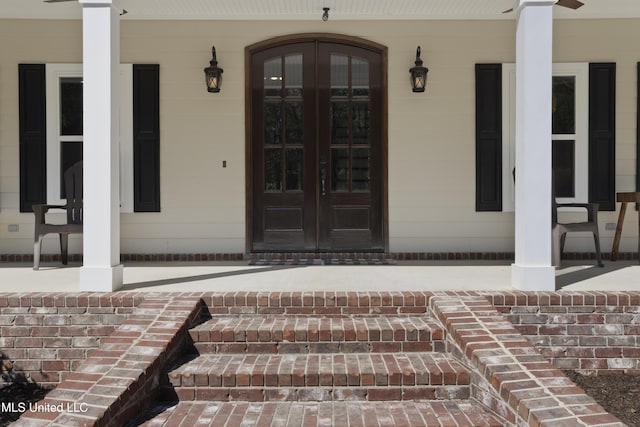 property entrance with french doors, covered porch, and brick siding