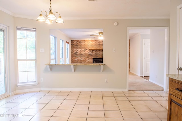 kitchen with ceiling fan with notable chandelier, decorative light fixtures, light stone counters, and ornamental molding