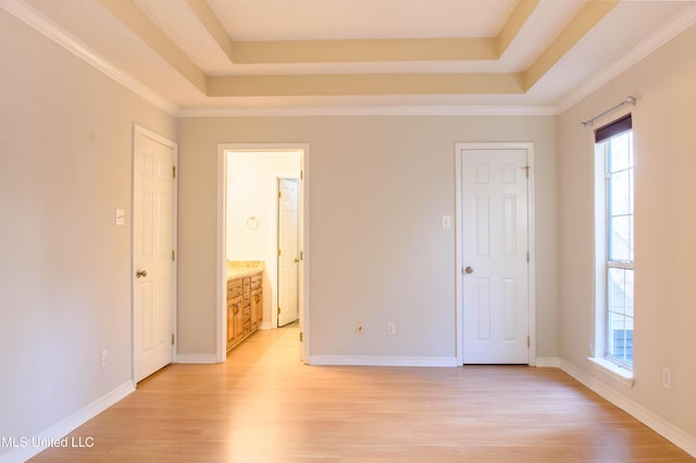 unfurnished room featuring light wood-type flooring, a raised ceiling, and crown molding