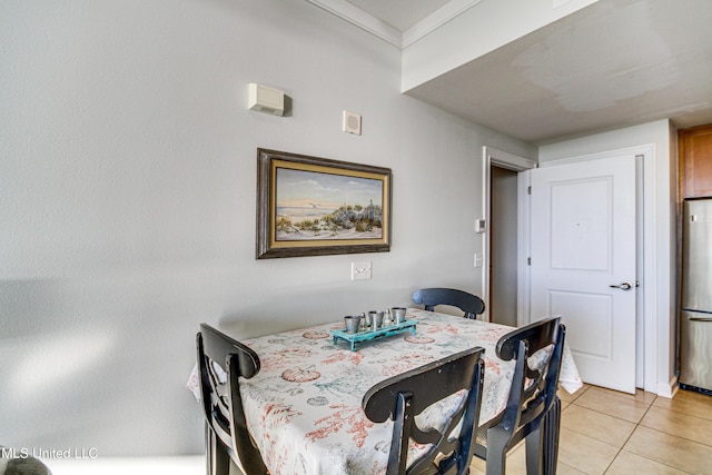 dining space with light tile patterned flooring and ornamental molding