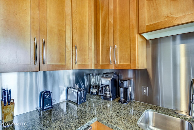 kitchen featuring dark stone countertops and a sink