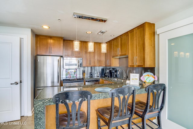 kitchen with brown cabinets, appliances with stainless steel finishes, a peninsula, and a sink