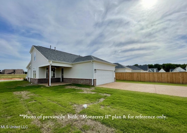 rear view of property featuring a garage and a lawn