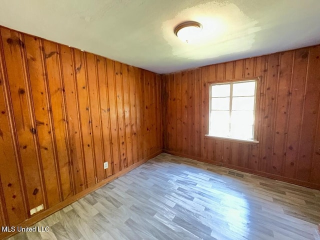 unfurnished room featuring wood walls, baseboards, and wood finished floors