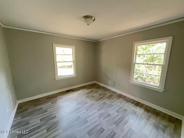 unfurnished room with ornamental molding, visible vents, baseboards, and wood finished floors