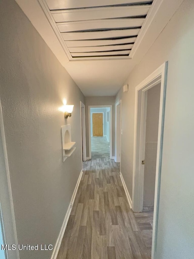 hallway featuring wood finished floors and baseboards