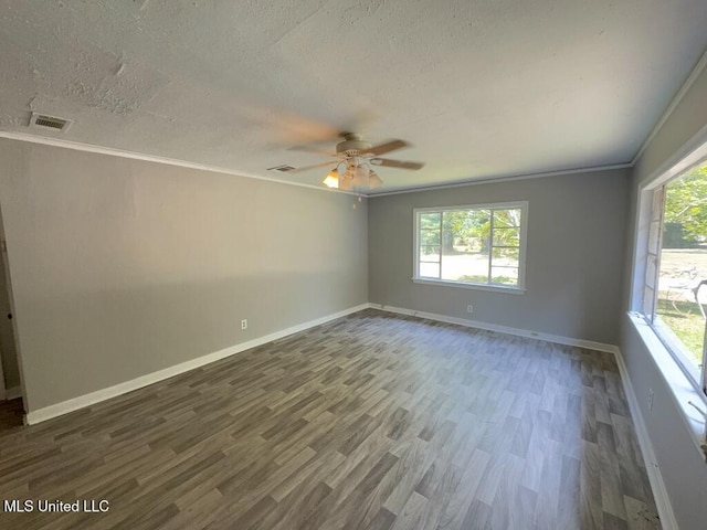 empty room with ornamental molding, visible vents, a textured ceiling, and wood finished floors