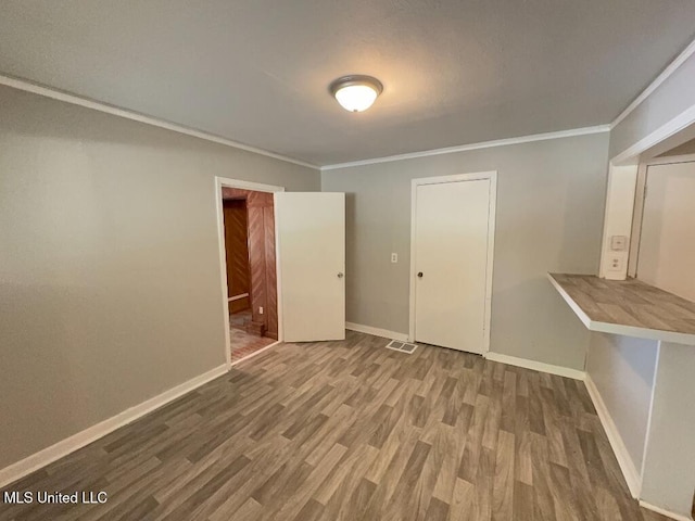 spare room with ornamental molding, wood finished floors, and baseboards