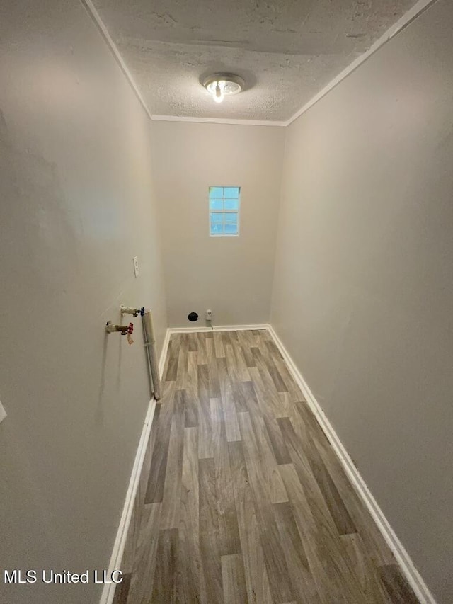 clothes washing area with crown molding, a textured ceiling, baseboards, and wood finished floors