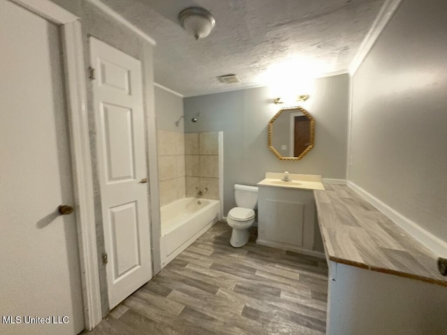 bathroom with toilet, shower / bathtub combination, wood finished floors, a textured ceiling, and vanity