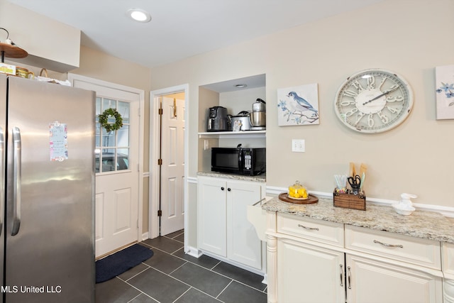 453 Cherry Tree Ln, Southaven, MS 38671 - kitchen with freestanding refrigerator, black microwave, dark tile patterned flooring, white cabinetry, and light stone countertops