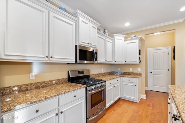 kitchen with crown molding, white cabinets, light hardwood / wood-style floors, and appliances with stainless steel finishes