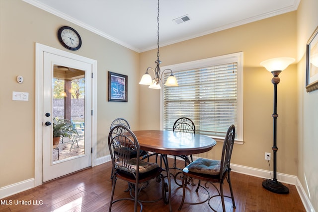 dining space with crown molding, dark hardwood / wood-style floors, and an inviting chandelier