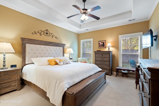 bedroom featuring ornamental molding, light colored carpet, ceiling fan, and a tray ceiling