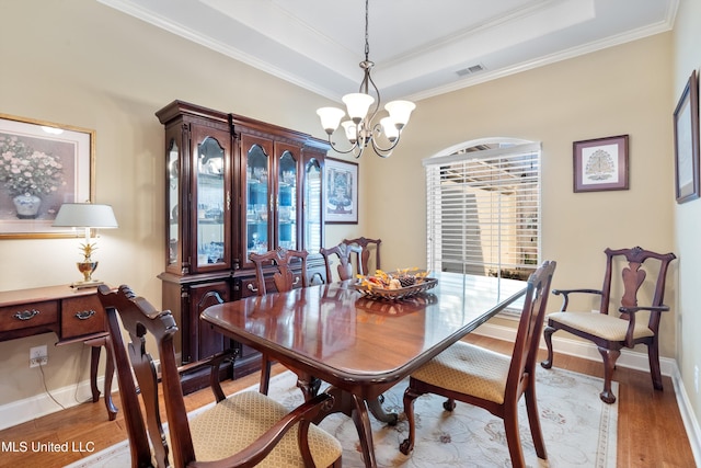 dining room with a tray ceiling, light hardwood / wood-style flooring, a wealth of natural light, and a notable chandelier