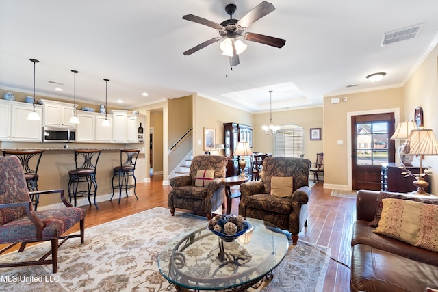 living room featuring ceiling fan with notable chandelier, light wood-type flooring, and ornamental molding