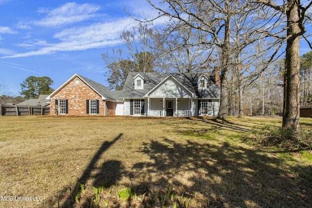 new england style home featuring brick siding, covered porch, and a front yard