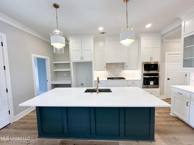 kitchen featuring an island with sink, light countertops, a sink, and oven