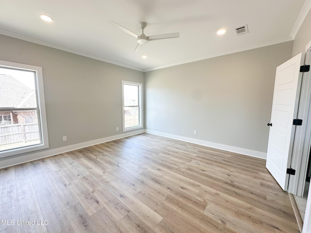 empty room with light wood-style flooring, a ceiling fan, visible vents, baseboards, and ornamental molding